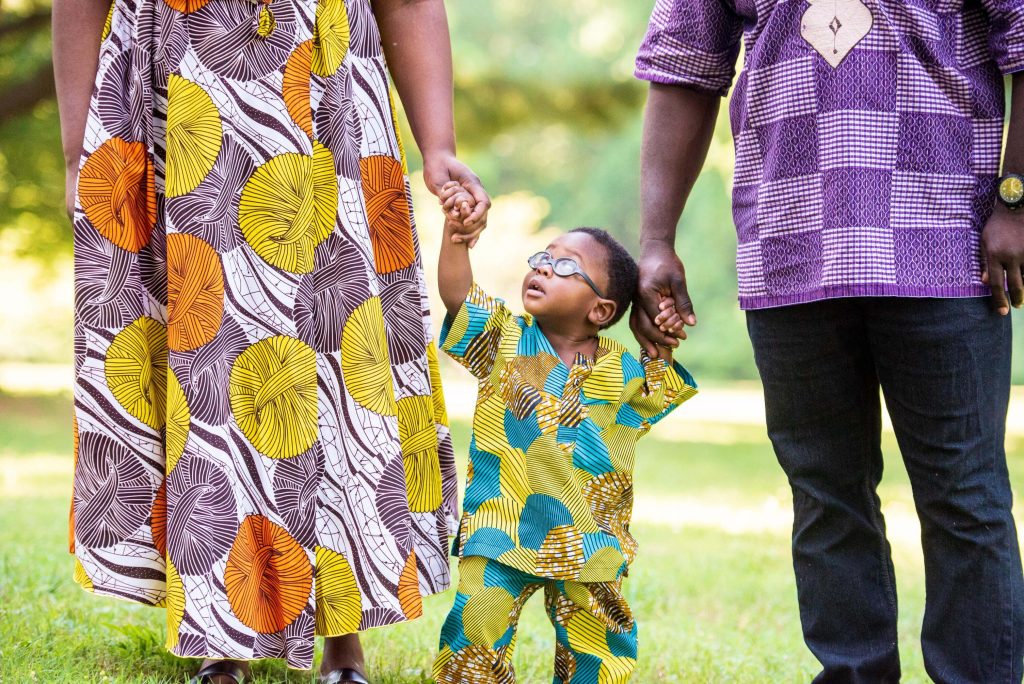 Sitou in African attire holding his parents' hands