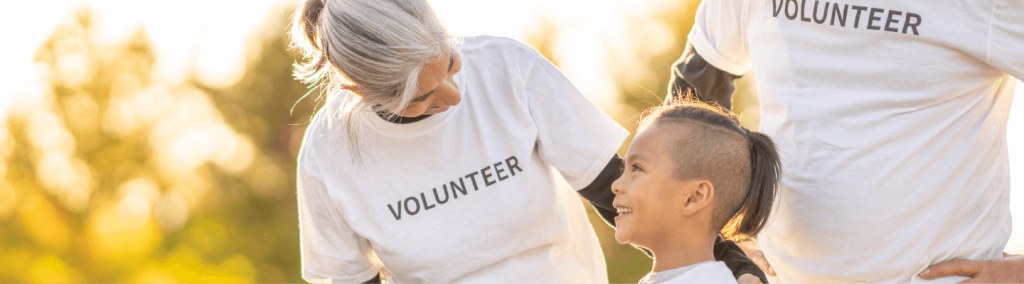 woman wearing Volunteer shirt smiling down at child