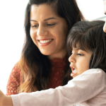 mother and father with preschooler looking at mobile phone