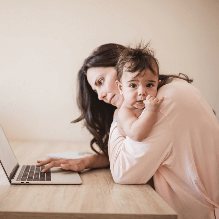 woman on laptop with baby in her arms