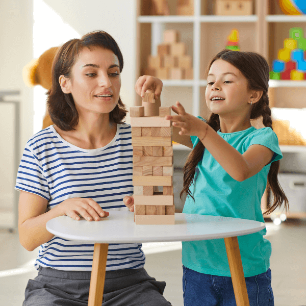 teacher building a block tower with a school-aged girl